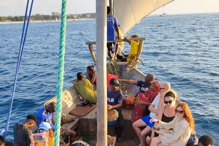 Tourists relax on a traditional dhow boat during a sunset cruise in Nungwi, Zanzibar, enjoying the serene ocean views.