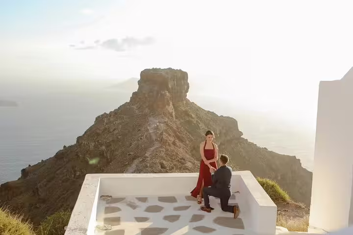 Sunset engagement proposal at Santorini cliff terrace with caldera backdrop, private photographer session