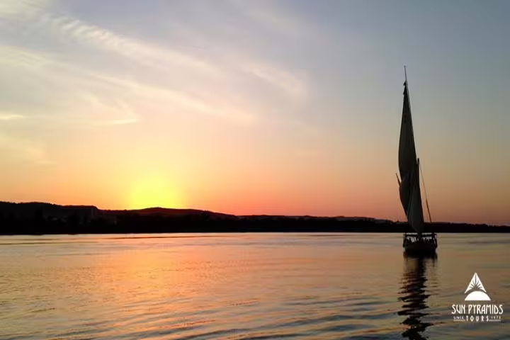 Sunset felucca ride on the Nile in Aswan, Egypt, with sailboat silhouette and golden water reflections