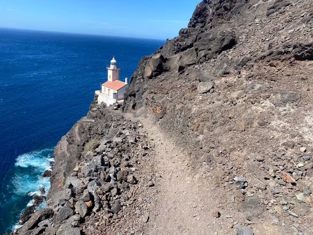 Rocky coastal path leading to Lighthouse Dona Amélia with stunning ocean views, perfect for a sunset hike adventure.