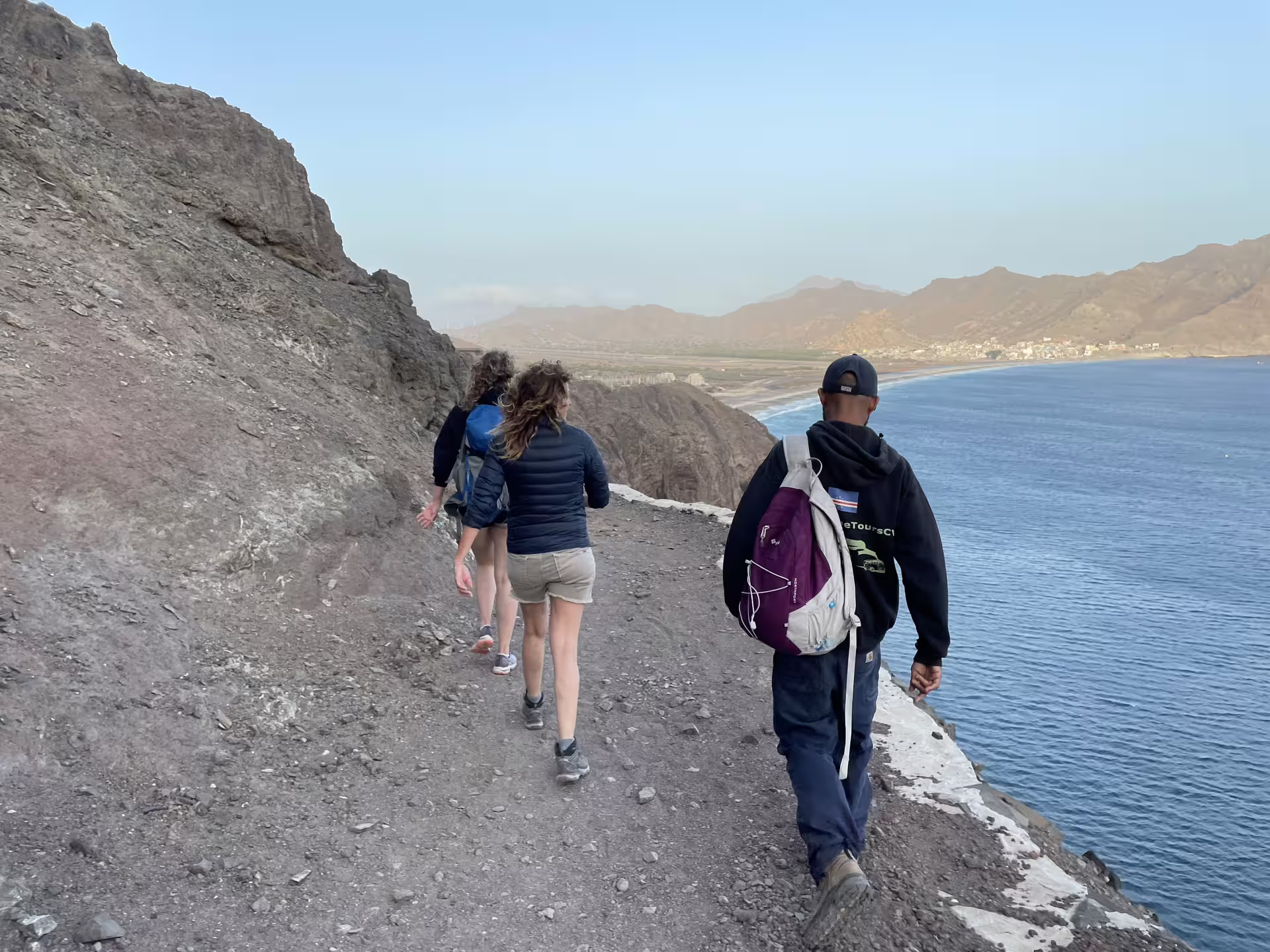 Hikers enjoy a scenic coastal path with ocean views on the Sunset Hike to Lighthouse Dona Amélia, perfect for adventure seekers.