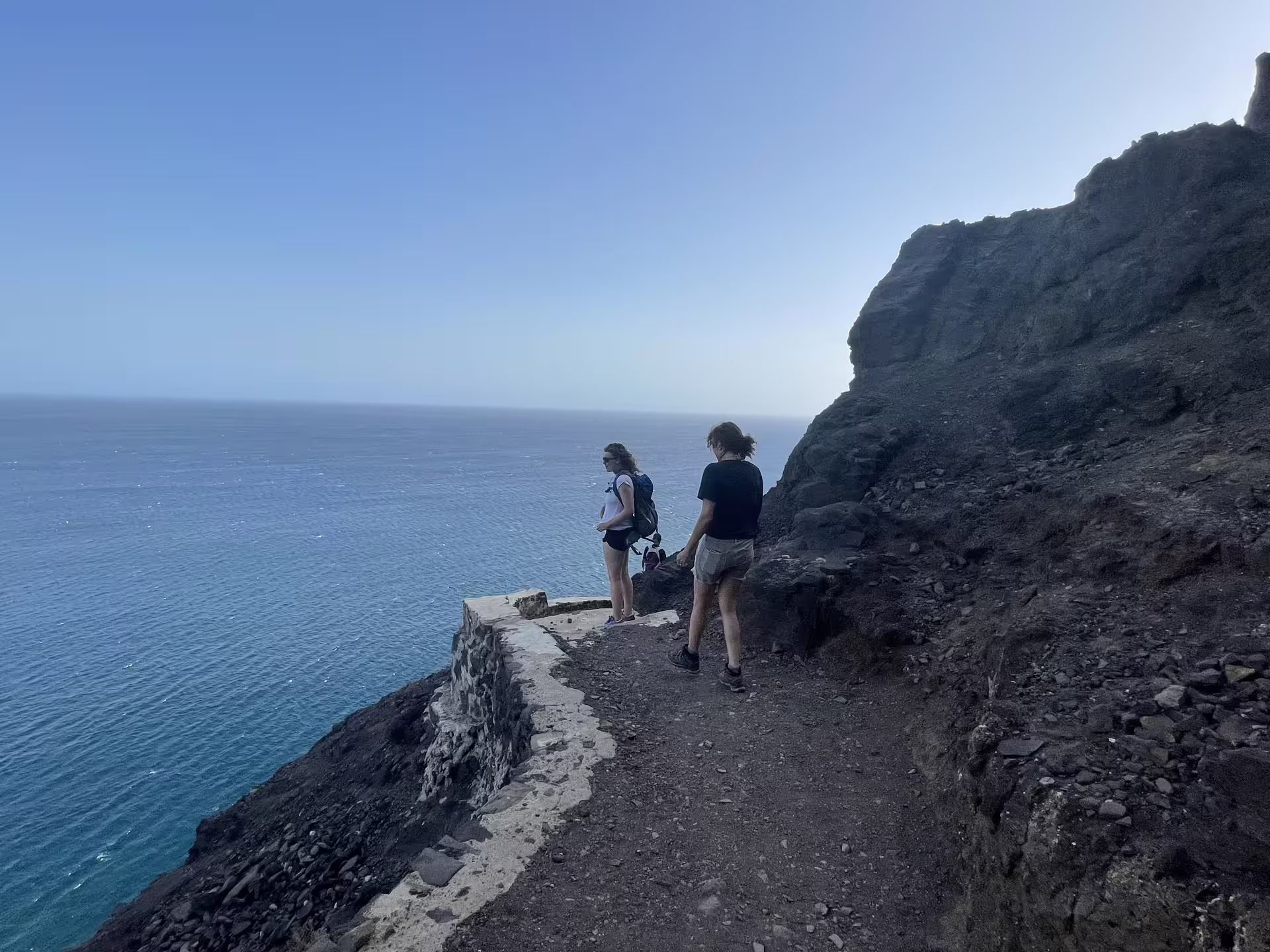 Hikers admire ocean views on the scenic Sunset Hike to Lighthouse Dona Amélia, showcasing rugged cliffs and serene waters.