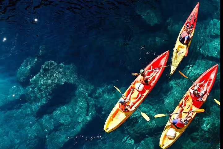 Aerial view of kayaks over crystal-clear water, coastal snorkeling stop during sunset kayaking with wine and water