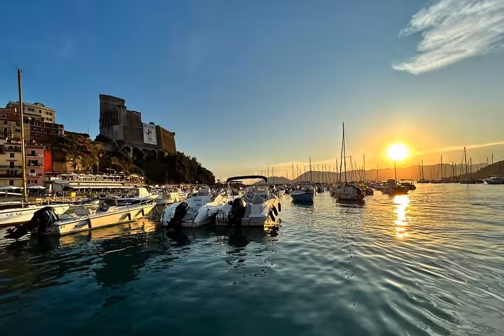 Sunset over Lerici harbor with boats and historic castle, perfect for a dreamy boat tour experience in La Spezia.