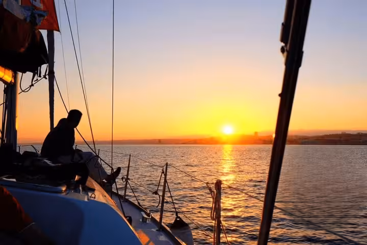 Experience a serene sunset sailing tour on the Tagus River, capturing stunning views of Lisbon's skyline and tranquil waters.