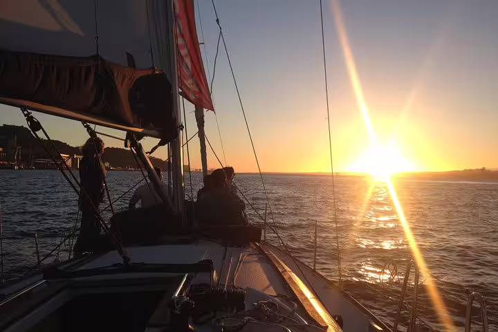 Sailing boat on the Tagus River at sunset, offering a scenic view of the glowing horizon and tranquil waters.
