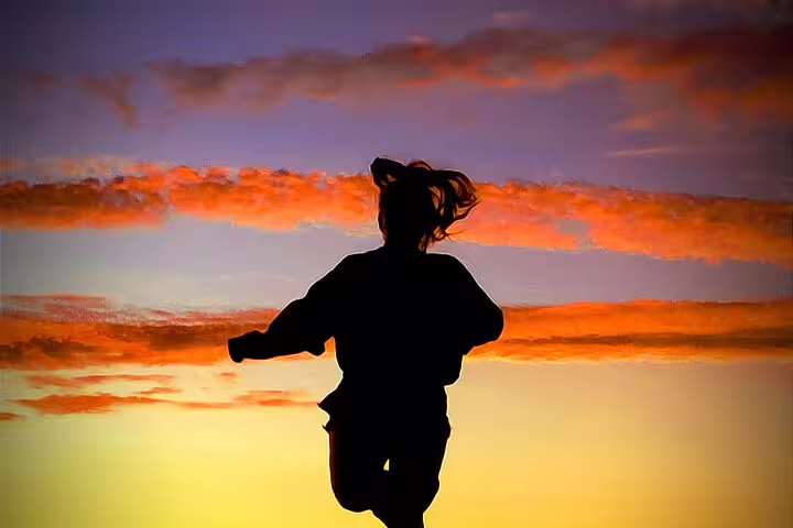 Silhouette of person jumping against a vibrant sunset sky on Algarve Natural Park off-road adventure.