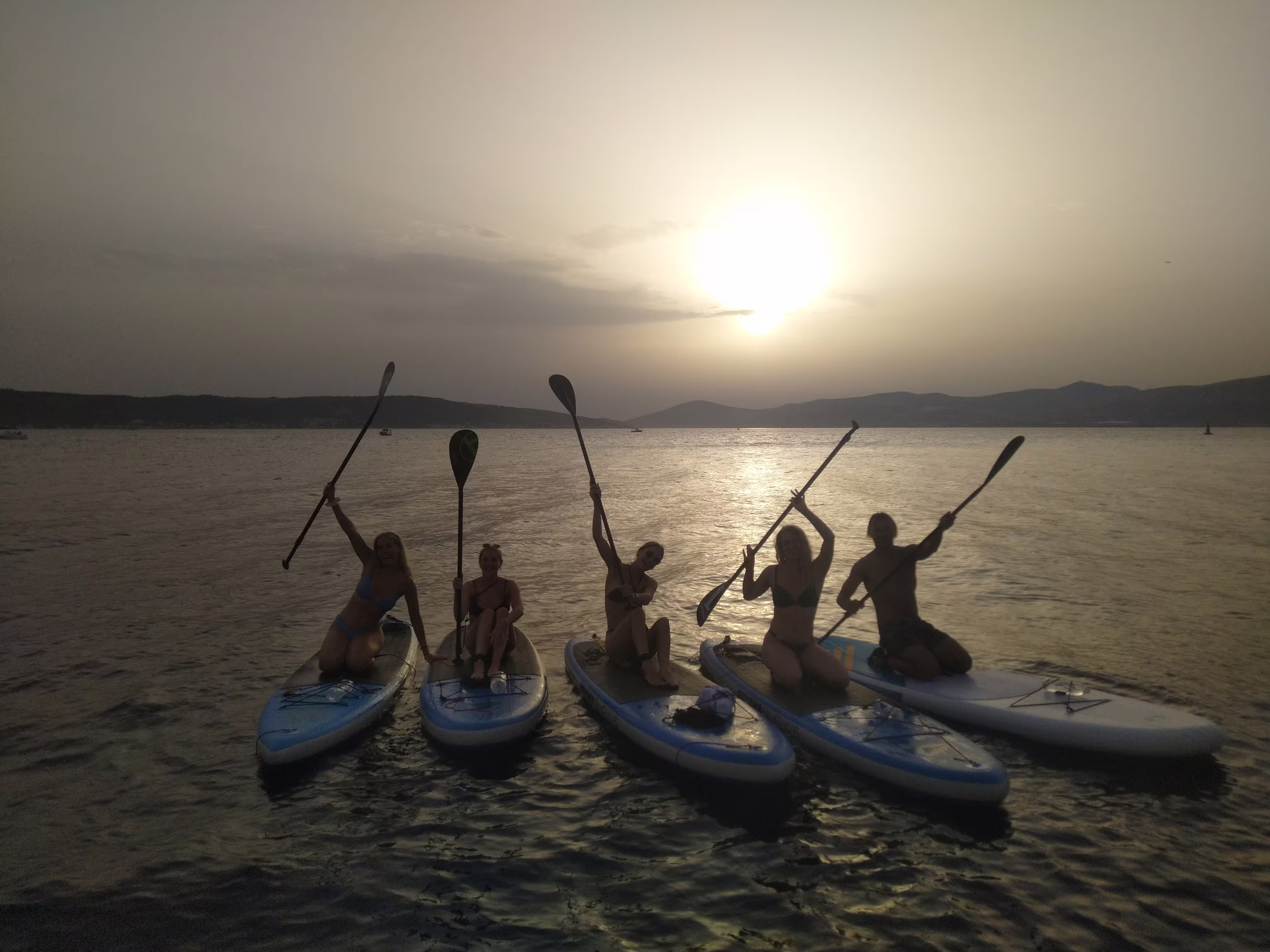 Sunset stand up paddle tour in Split with group on SUP boards, paddles raised on the Adriatic Sea