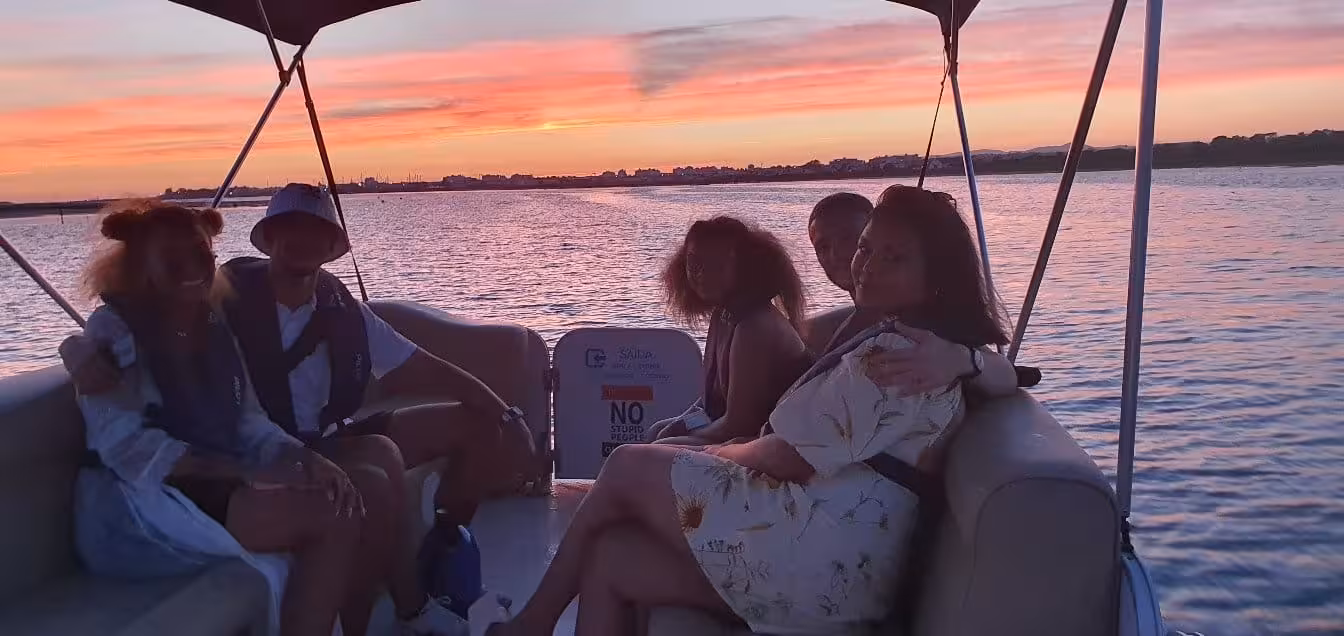 Group enjoying a serene sunset cruise on a boat, capturing the vibrant hues of a beautiful evening sky.