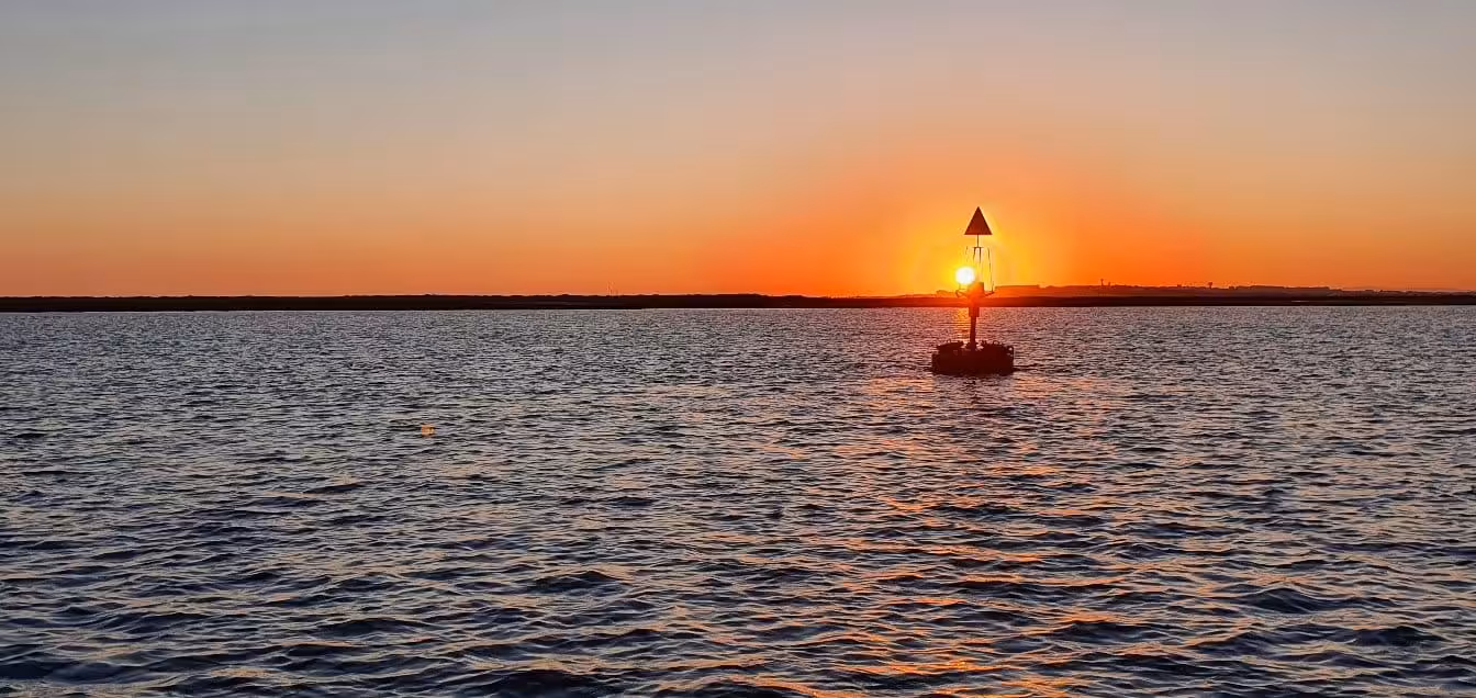 Sunset Tour Privado features a buoy silhouetted against a vibrant sunset over tranquil ocean waters.
