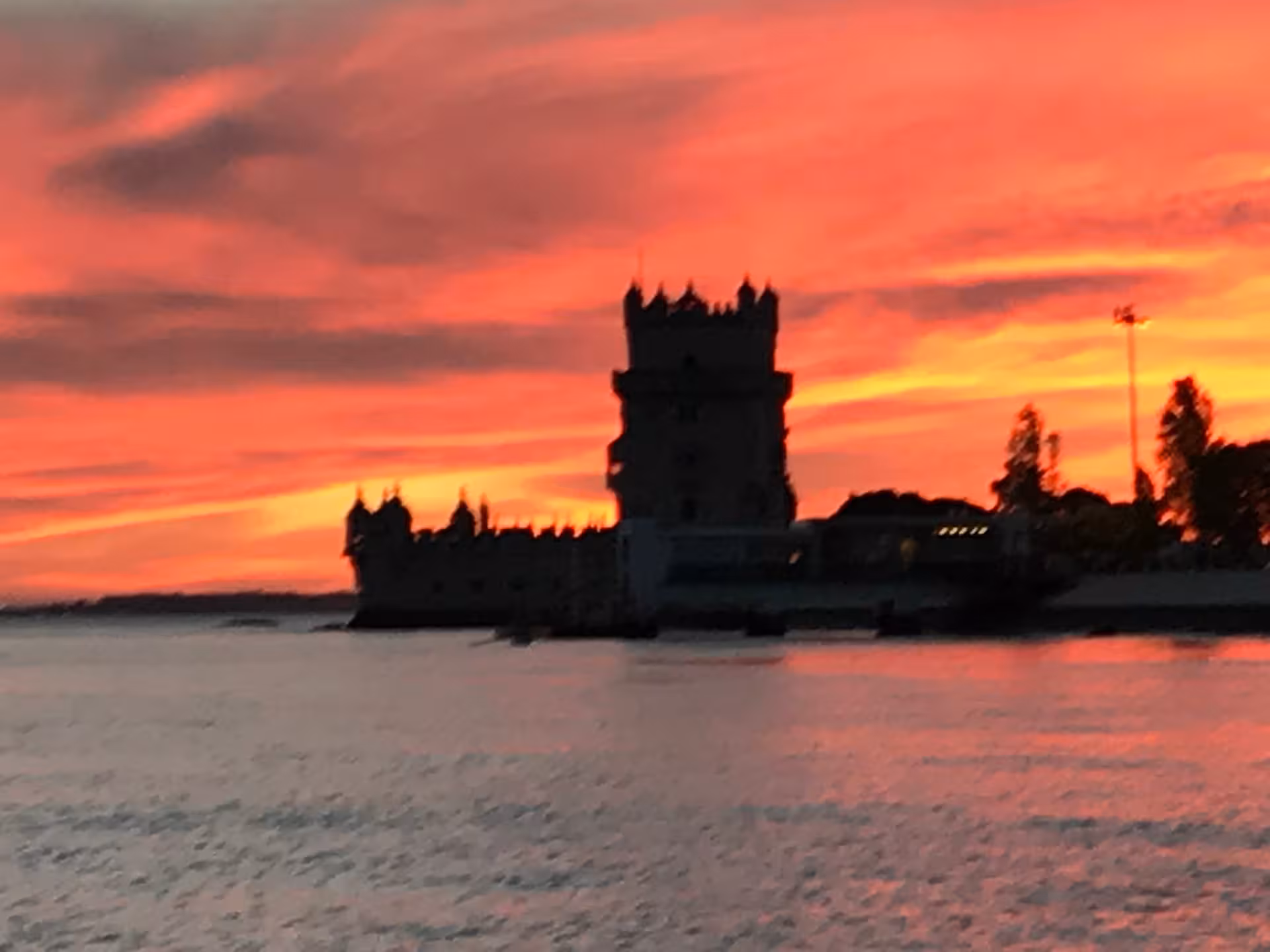 Fiery sunset behind Belém Tower on Lisbon VIP catamaran cruise with wine tasting on the Tagus River