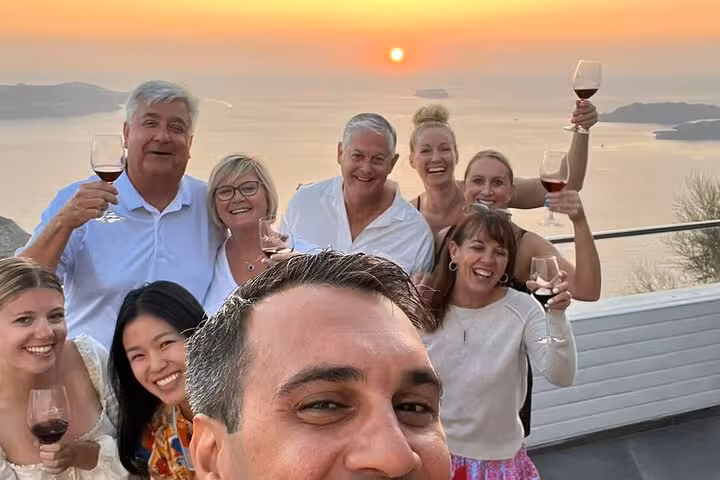 Guests toast red wine at sunset on private tour, visiting 3 wineries with tapas and sea views