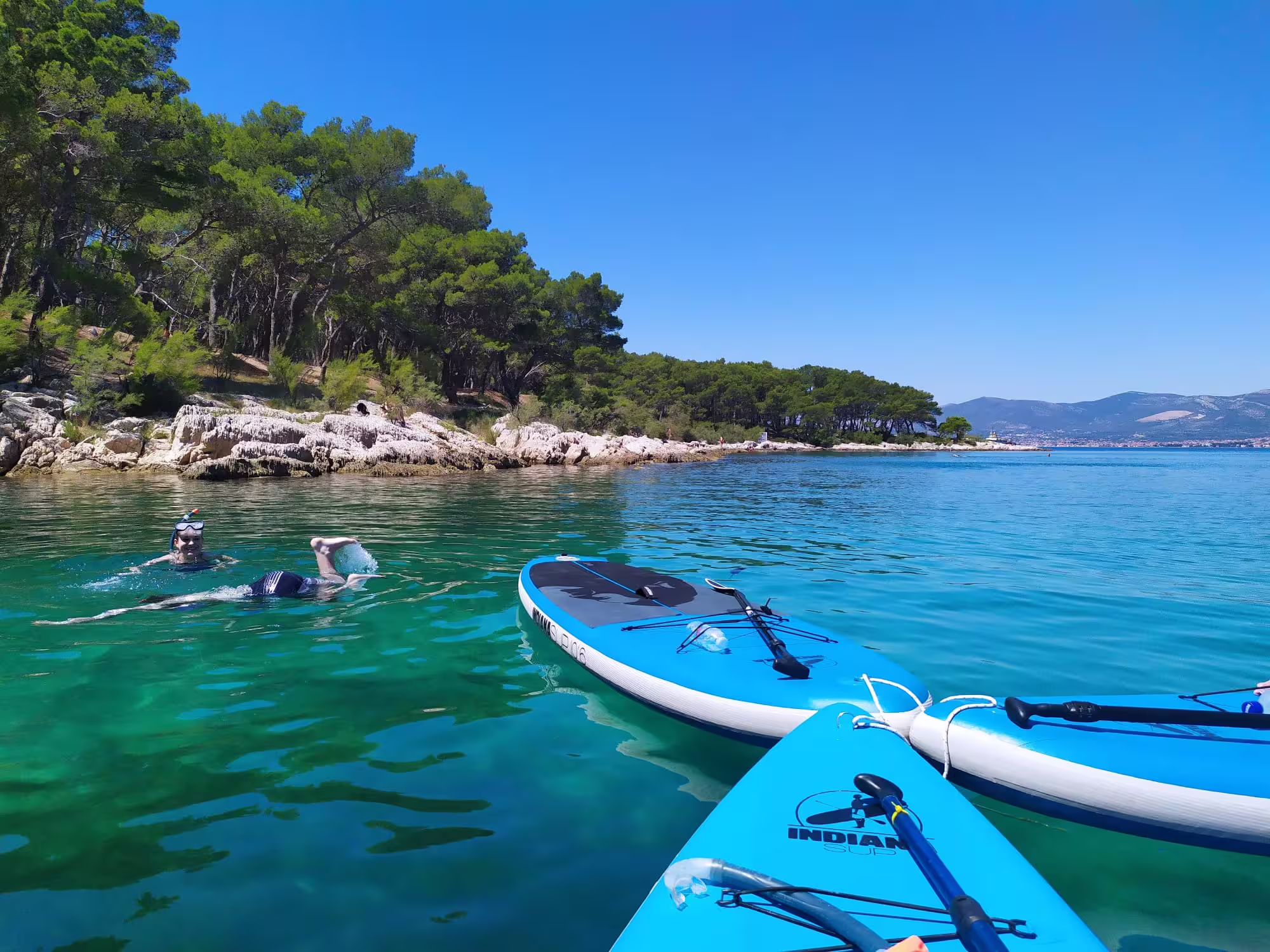 SUP boards and snorkeler in crystal-clear Adriatic bay on a stand up paddle tour from Split, Croatia