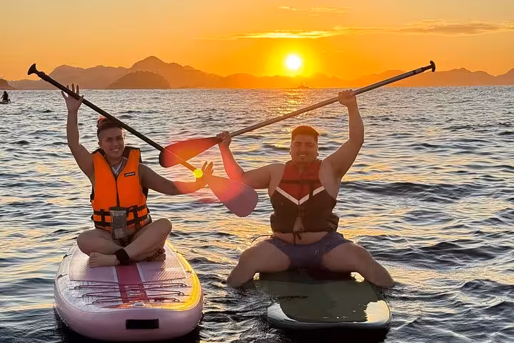 Two friends joyfully paddleboarding at Copacabana sunrise, capturing the essence of river exploration and adventure.