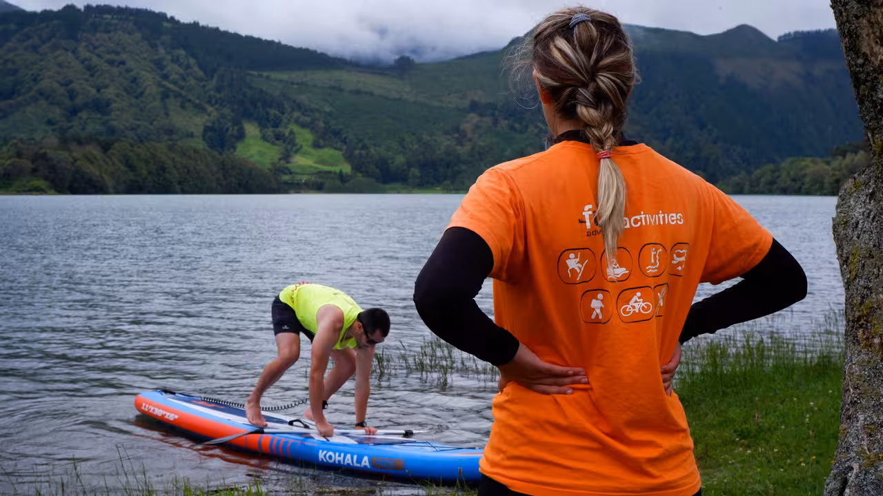SUP Rental Seven Cities guide coaching a beginner on a paddleboard beside the calm volcanic lake in Sete Cidades, Azores