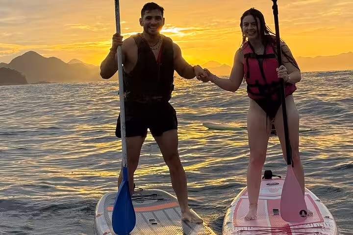 Couple sharing a stand-up paddleboarding moment at sunrise in Copacabana, experiencing the river DE anew.