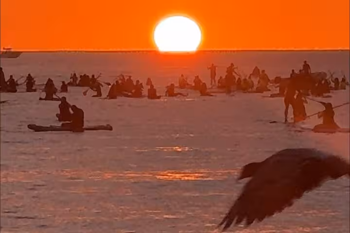 Group of paddleboarders enjoying a stunning sunrise over Copacabana waters, perfect for a sunrise SUP adventure.