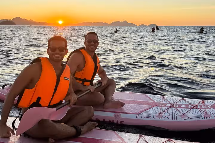 Two friends paddleboarding at sunrise in Copacabana, showcasing a vibrant river DE adventure.