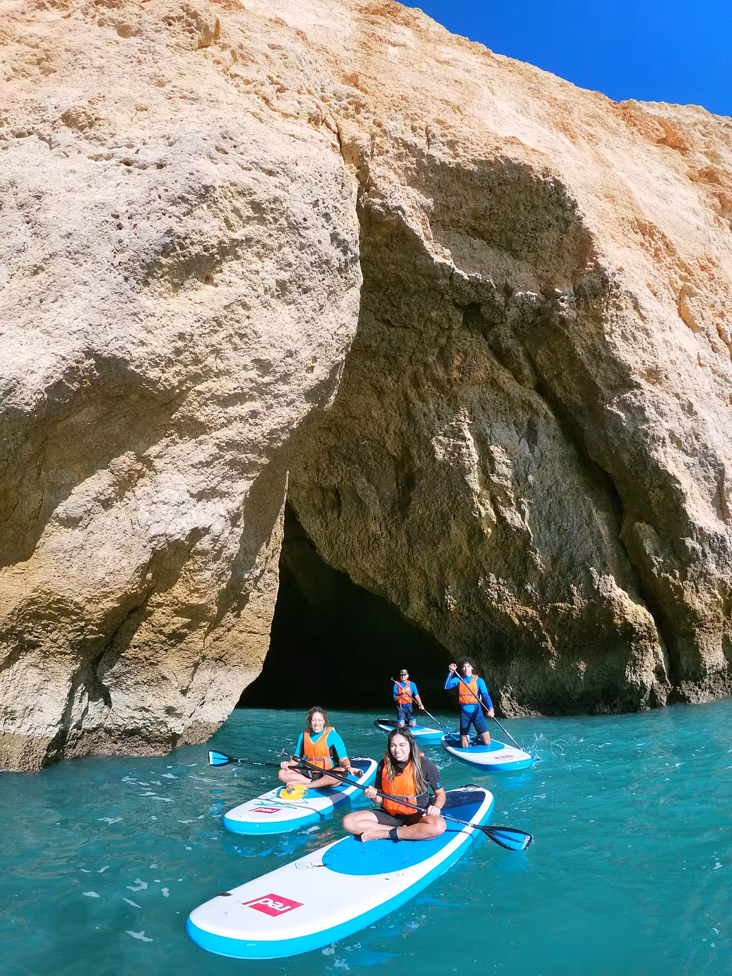Group on stand up paddle boards exploring turquoise sea and dramatic caves on a guided Algarve coast SUP tour