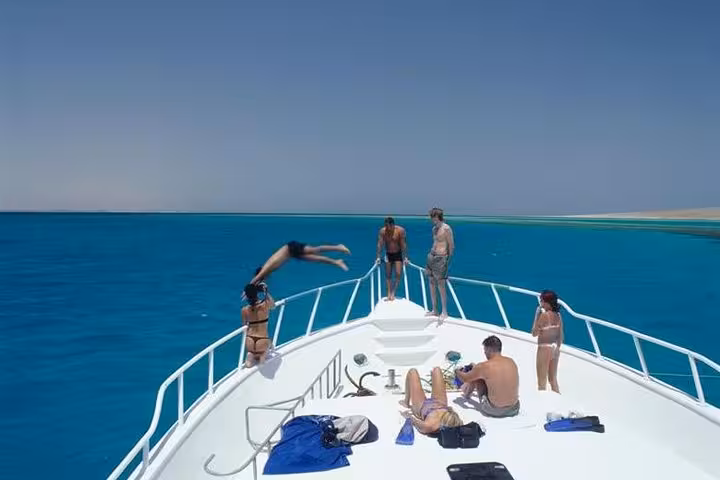 Super Giftun Island boat trip with guests sunbathing and diving into crystal-clear Red Sea near sandbanks