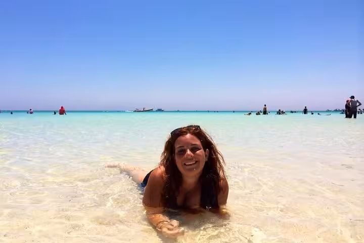 Traveler relaxing in shallow crystal-clear water on Super Giftun Island beach, Red Sea snorkeling day trip