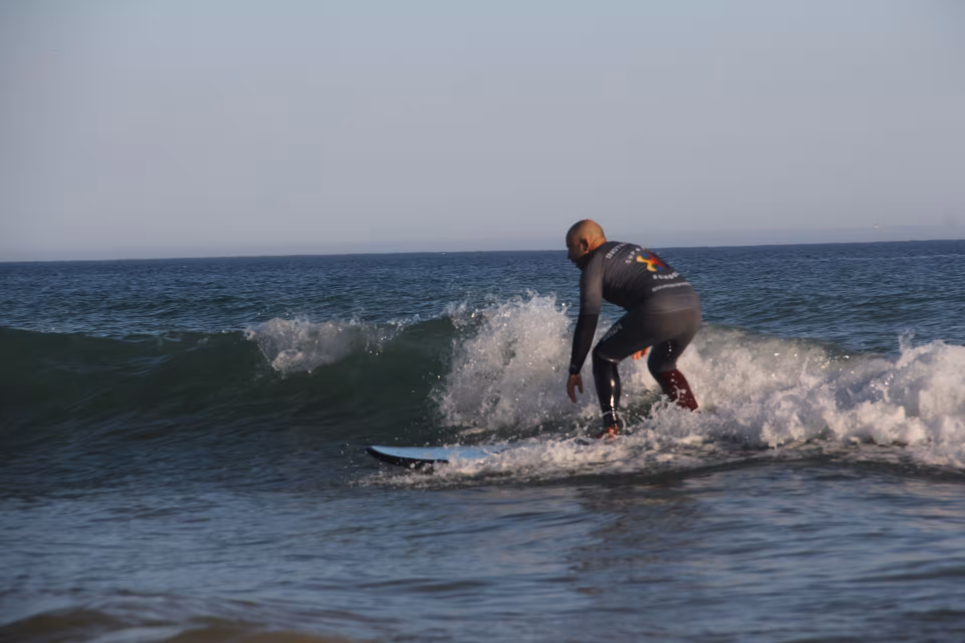 Surf instructor demonstrating balance on a breaking wave in a surf experience clinic on a peaceful coastal beach