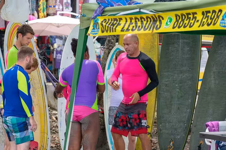 Group of surf instructors and students preparing for lessons under a tent in Manuel Antonio, showcasing lively beach vibes.