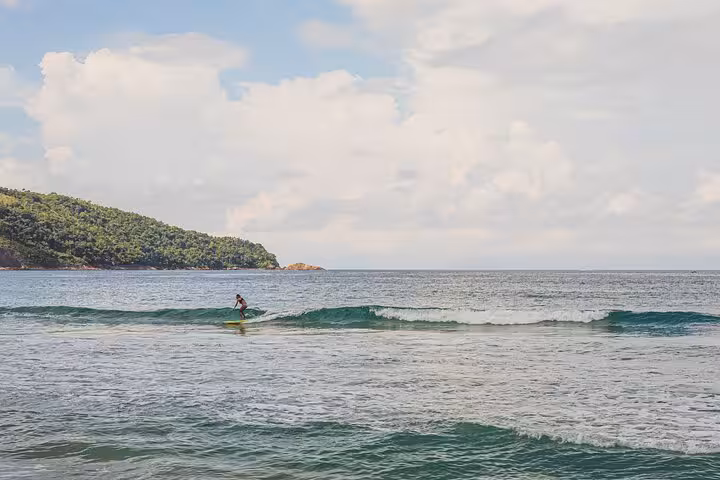 Surfer riding gentle waves at Sono Beach during an adventure tour with Paraty Tours.