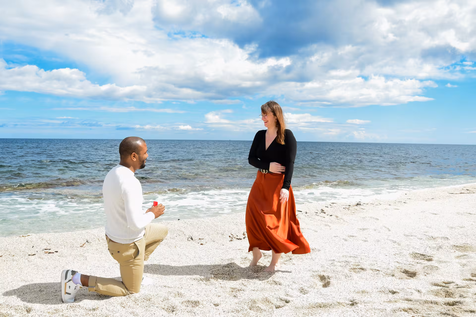 Man proposing on one knee at a sunny beach in Heraklion Venetian Port, surprising his partner.