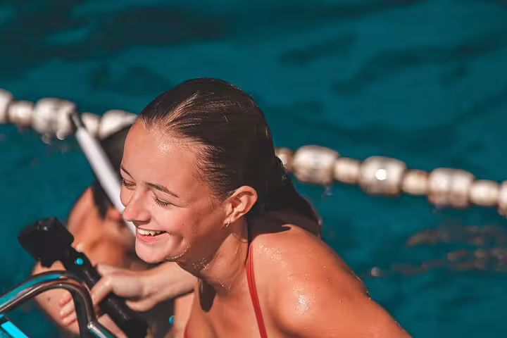 Smiling swimmer climbing boat ladder in Blue Lagoon, a stop on the scheduled 3 Islands speedboat tour