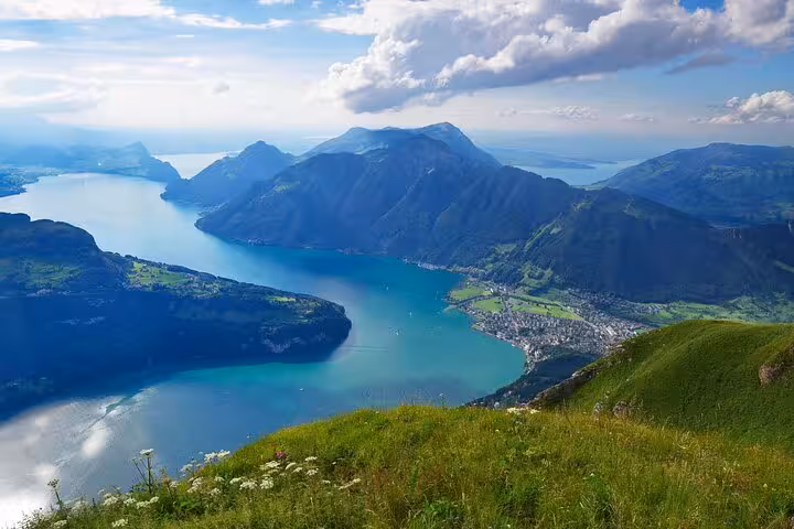 Breathtaking panorama of Swiss Alps and lakes, featuring vibrant greenery and dramatic peaks.
