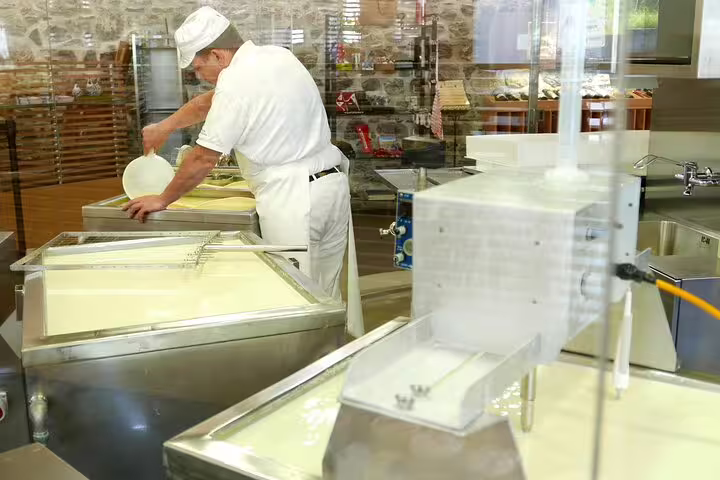 Cheesemaker in traditional attire crafting Swiss cheese in Engelberg during Zurich small group tour.