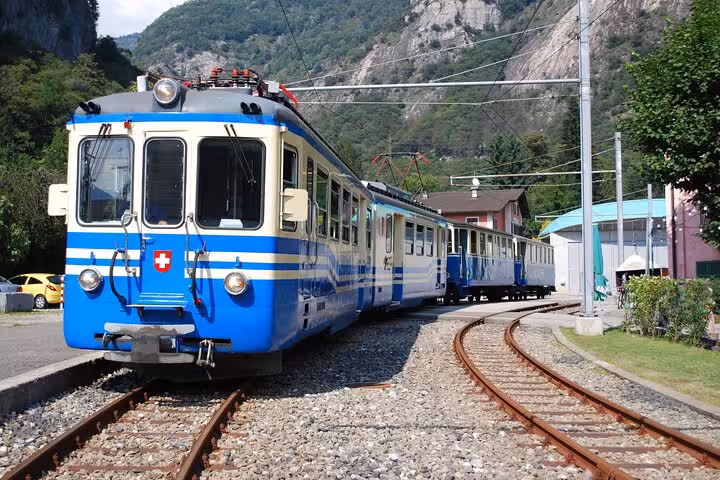 Classic blue Swiss train navigating a winding track amidst mountainous terrain, a must-see for train aficionados.