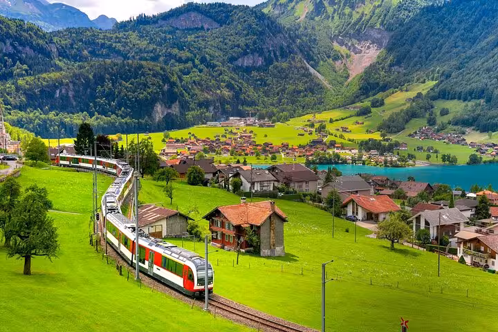 Panoramic Swiss train journey passing through lush green valleys and picturesque villages, ideal for train enthusiasts.
