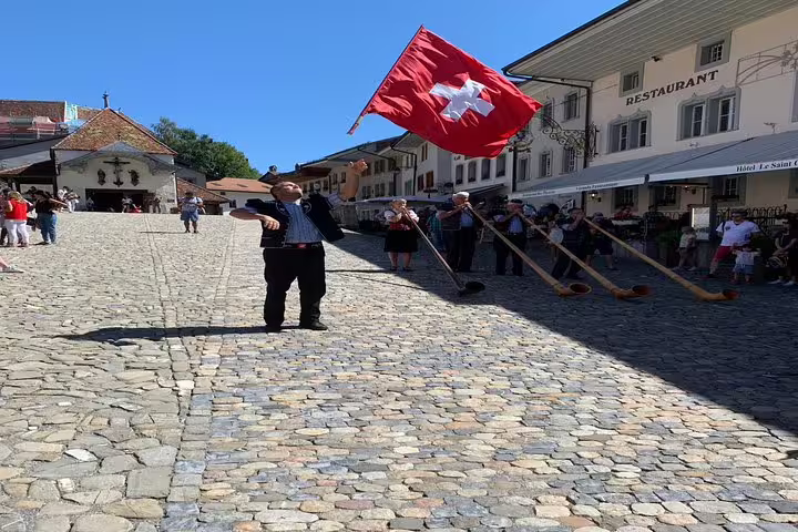 Traditional Swiss flag performance and alphorn players in a charming Gruyères village setting.