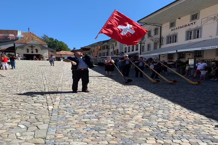 Traditional Swiss flag bearer and alphorn players in a cobblestone square on the Bern Small Group Tour.