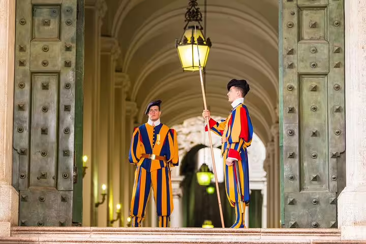 Swiss Guards in traditional uniforms standing at a grand Vatican entrance on a guided Rome Vatican Museums and Sistine Chapel tour