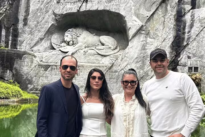Tourists enjoy scenic views of the Lion Monument in Lucerne, a highlight of the Swiss panoramic train journey.