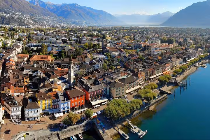 Aerial view of picturesque Swiss town by the lake, showcasing mountains and colorful architecture for a guided tour.