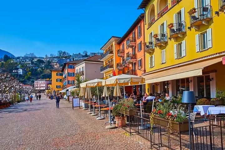 Sunny Swiss promenade with vibrant buildings and lively outdoor cafes in a scenic town square.