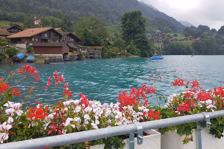 Charming Swiss village by a turquoise lake with vibrant flowers and mountain backdrop, ideal for a private tour experience.