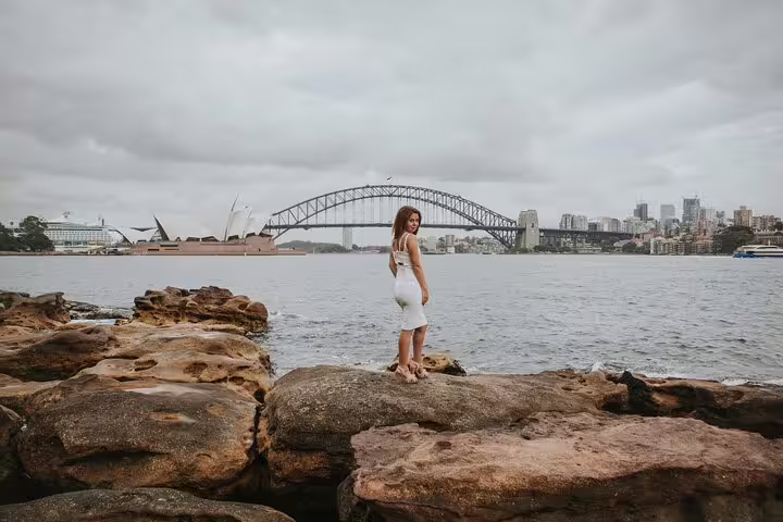 Woman posing on rocks with Sydney Opera House and Harbour Bridge on private Sydney travel photographer tour