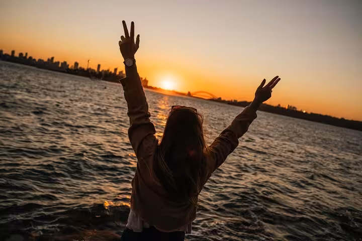 Person enjoying a vibrant sunset over Sydney Harbour, capturing the iconic skyline on a Sydney private tour.