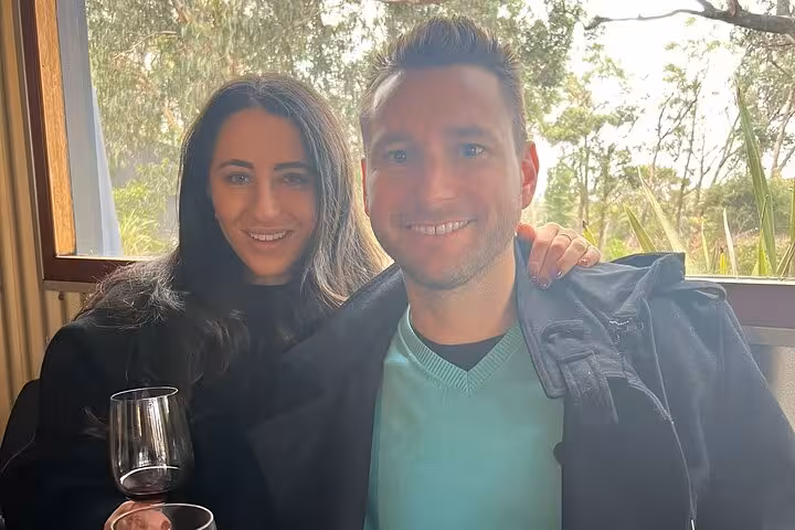 Couple enjoying a wine tasting experience in Sydney's Southern Highlands with scenic forest views.