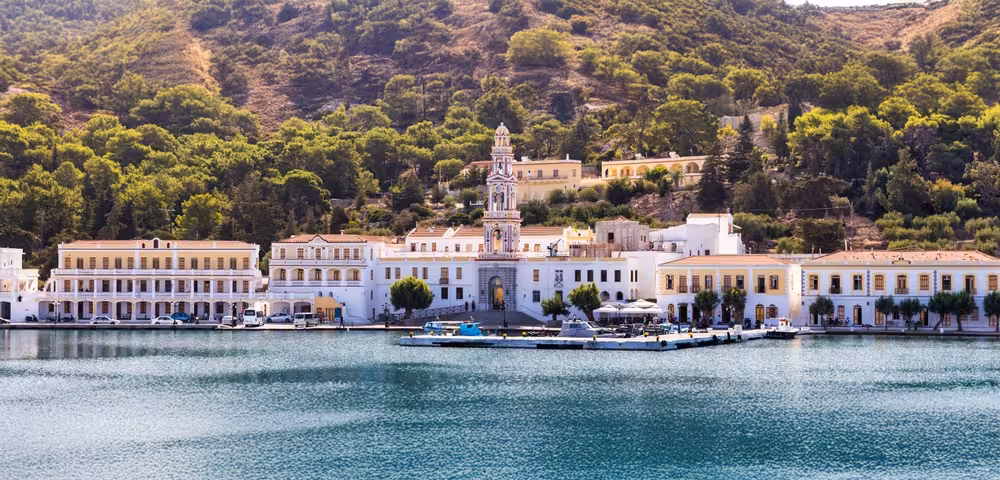 Symi Greece waterfront panorama with bell tower and pastel mansions, seen on a Discover Symi Axopar 25 CT cruise