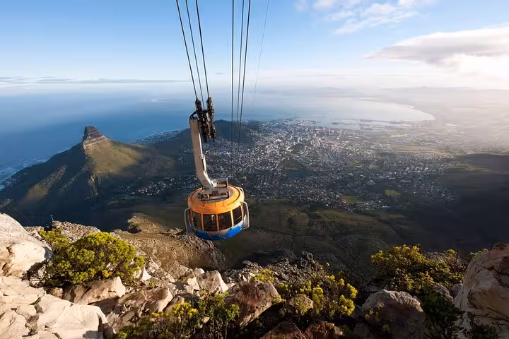Table Mountain cable car descends with panoramic views of Cape Town and the Atlantic Ocean in the background.