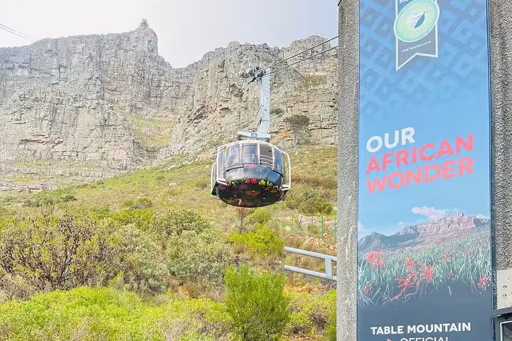 Cable car ascending Table Mountain with a promotional banner, showcasing iconic Cape Town views.