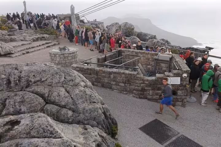 Visitors line up at the top of Table Mountain, enjoying panoramic views as part of a private Cape Town tour.