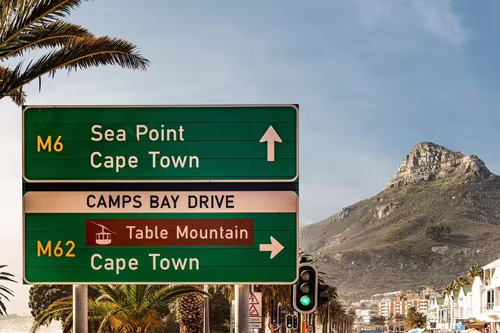 Road signs directing to Cape Town and Table Mountain with a scenic mountain view in the background.