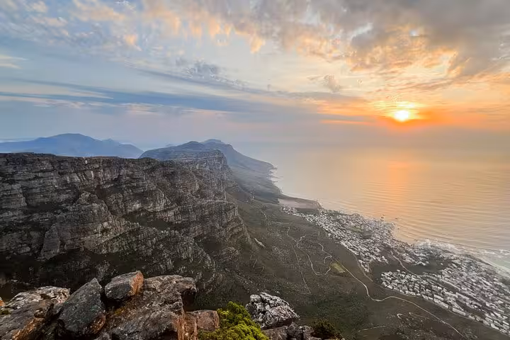 Breathtaking sunset over Table Mountain with dramatic cliffs and coastline, capturing Cape Town's natural beauty.